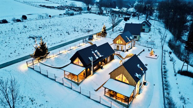 Un paisaje nevado con un grupo de casas de madera conectadas por una cerca.