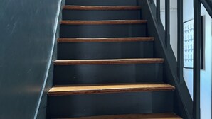 Una escalera con escalones de madera y barandillas negras.
