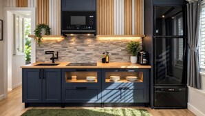 A modern kitchen with a built-in microwave, a black refrigerator, and a stone backsplash. - Private Cinematic Zen Loft\Spa Tub — 6PM–10AM (Orlando)