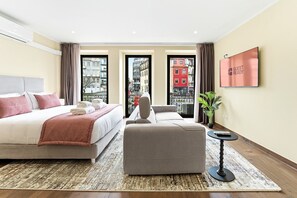 A modern hotel room with a large bed, a sofa, a small table, and a TV. - GuestReady - Poveiros Flats (Porto)