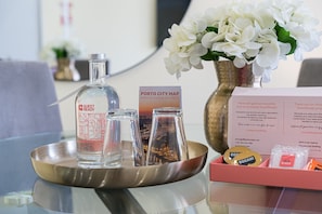 A hotel room with a tray table, a bottle labeled "Guest Ready," a glass, a "Porto City Map," and a "Thank you for choosing GuestReady!" sign. - GuestReady - Poveiros Flats (Porto)