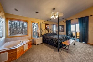Een slaapkamer met een hemelbed, een groot raam met zonwering, een plafondventilator en een balkon met uitzicht.