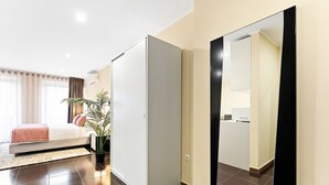 Een moderne hotelkamer met een bed, een grote spiegel, een kledingkast en een potplant.
