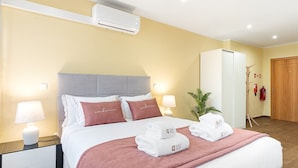 Ett hotellrum med en säng, sänglampor, en växt och en garderob.