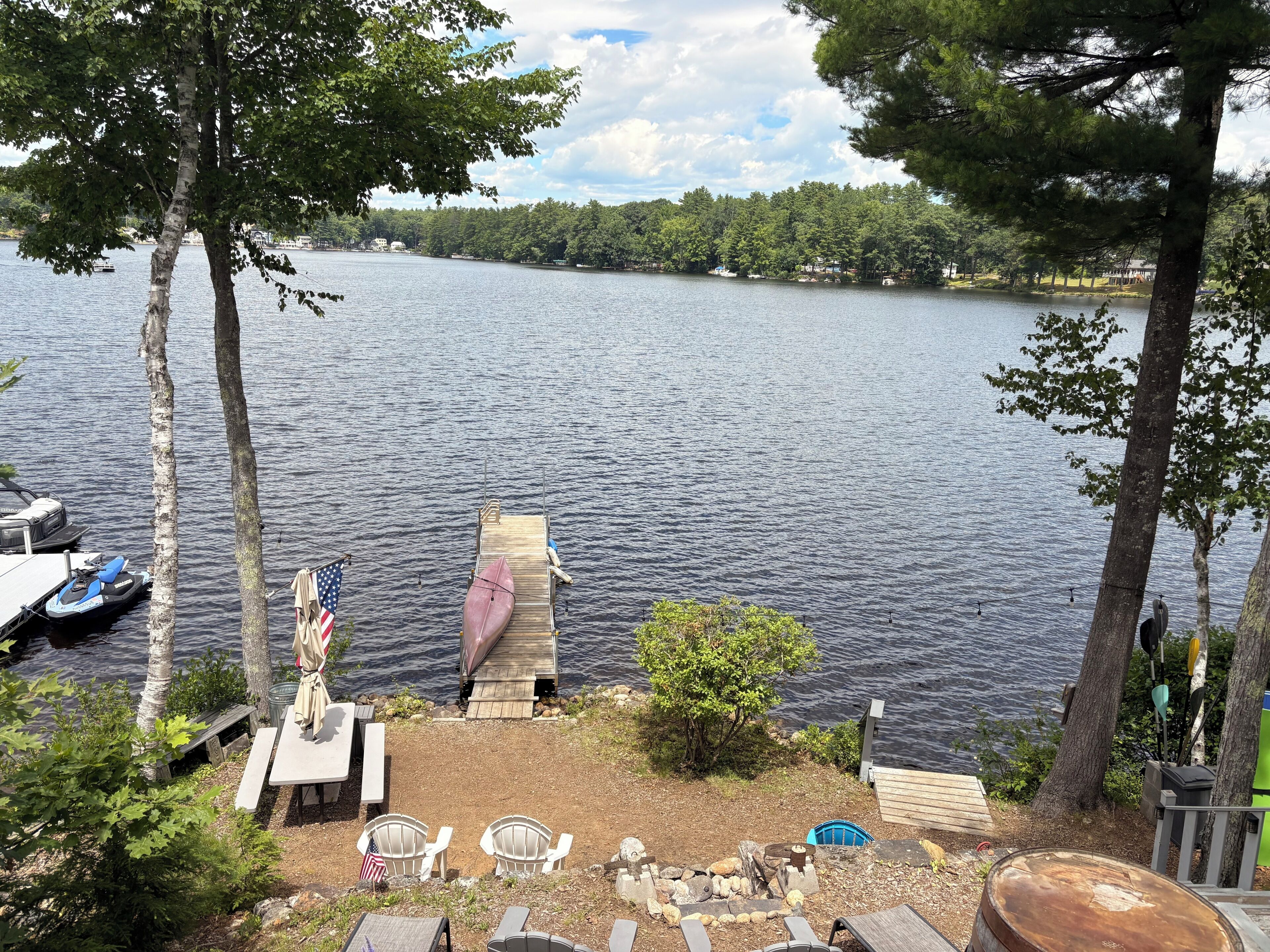 A lakeside view with a dock, boats, and outdoor seating.