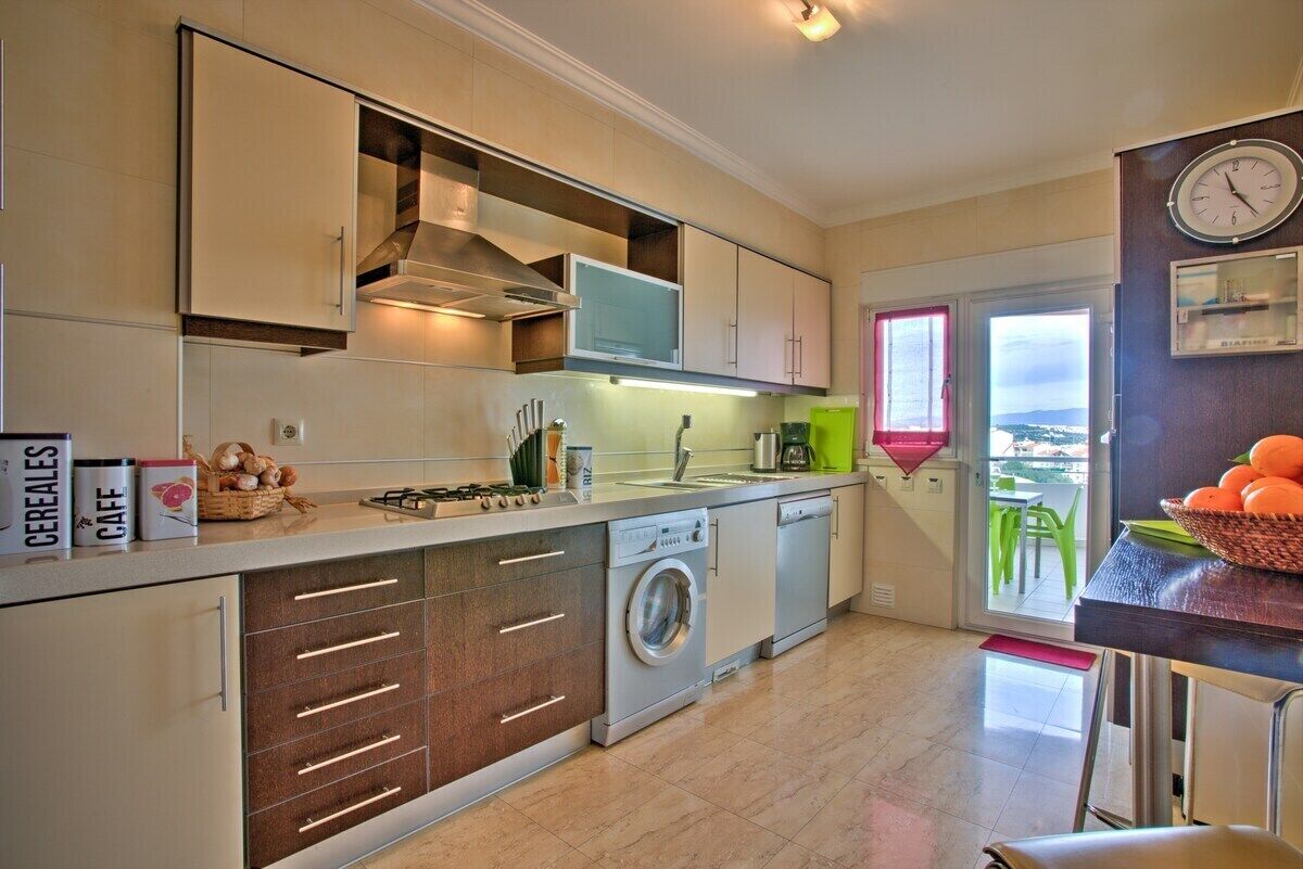 Een moderne keuken met inbouwapparatuur, een wasmachine en een eethoek met uitzicht.