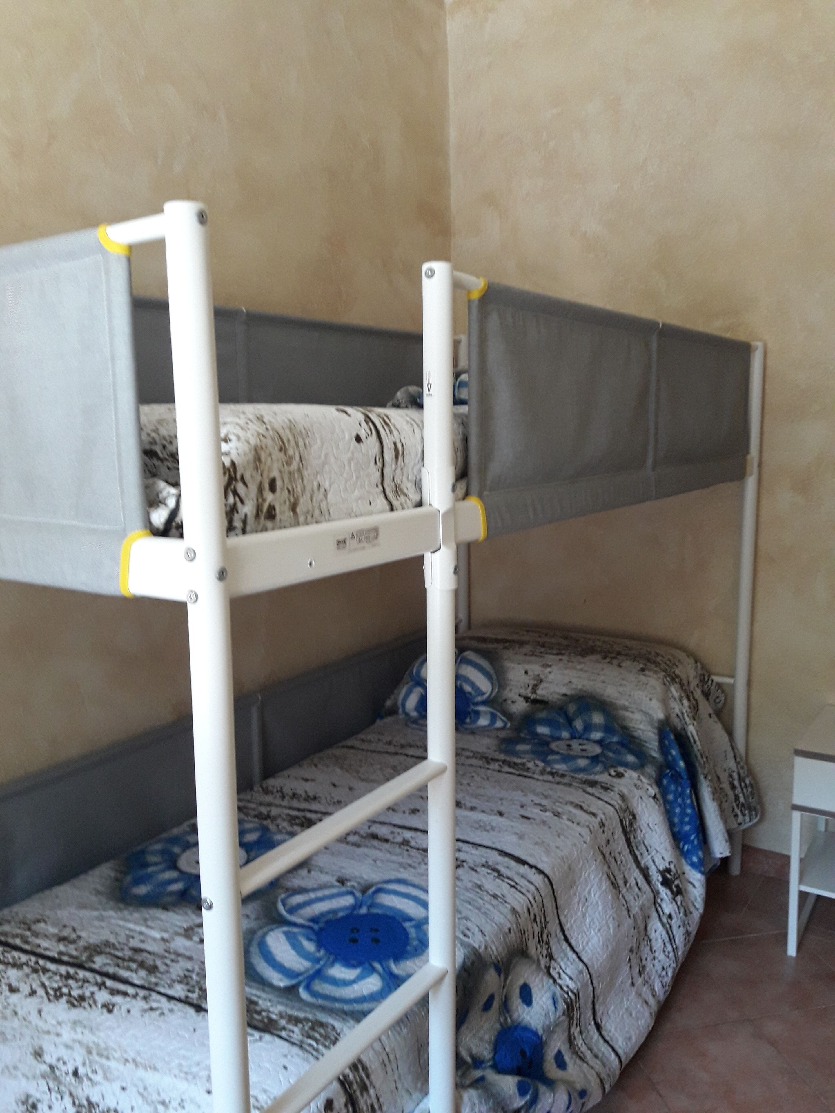A bunk bed with a grey canopy and a lower bed with a patterned bedspread.