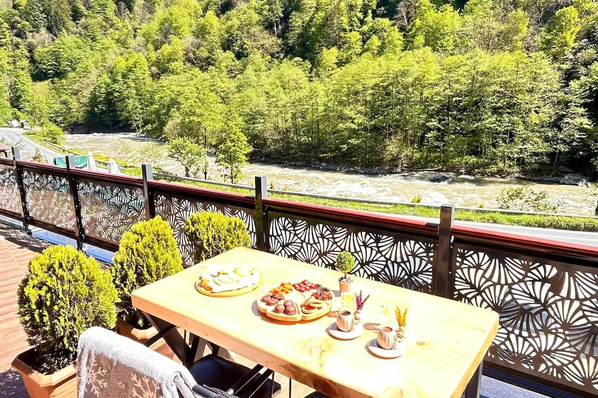 A table set outdoors with a view of a river and forested hills.