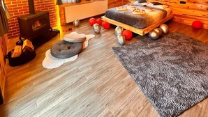 Een gezellig houten kamer ingericht in chaletstijl, met een bed, een open haard en een rustieke houten inrichting.