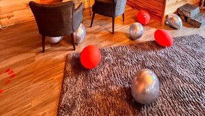 Een gezellige kamer met houten inrichting, een flatscreen televisie aan een bakstenen muur, een pooltafel en een eethoek met stoelen.