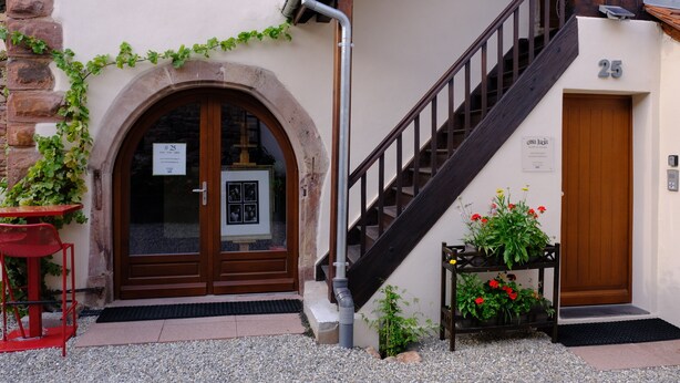 A building entrance with a wooden door, a staircase, and a small table with flowers. - 30-square-meter air-conditioned studio in the heart of Obernai—quiet and comfortable, with a fully equipped kitchen (Obernai)