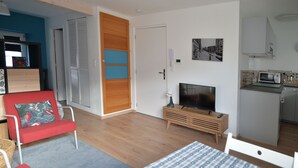 A compact living space with a television, kitchenette, and a red chair. - 30-square-meter air-conditioned studio in the heart of Obernai—quiet and comfortable, with a fully equipped kitchen (Obernai)