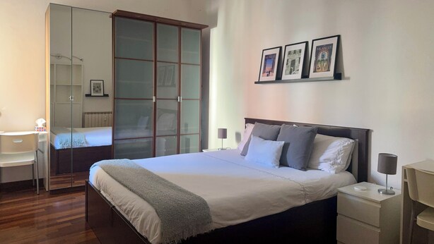 A bedroom with a bed, bedside tables, a desk, a wardrobe, and framed pictures on the wall. - B91 by VIDI · Bright Milanese flat near Navigli, direct tram to Duomo (Milano)