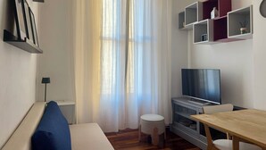A modern living room with a sofa, a small round table, a TV, and a fireplace. - B91 by VIDI · Bright Milanese flat near Navigli, direct tram to Duomo (Milano)