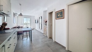 A modern kitchen with a dining area, large windows, and a view of the outdoors. - LA PLAGE Roses / Roses - INTERimmo (Rosas / Roses)