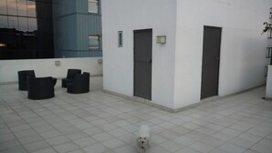 En gårdhave med fliset gulv, en hvid bygning og en sort hund i bevægelse.