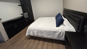 Et soveværelse med seng, kommode og garderobeskab.