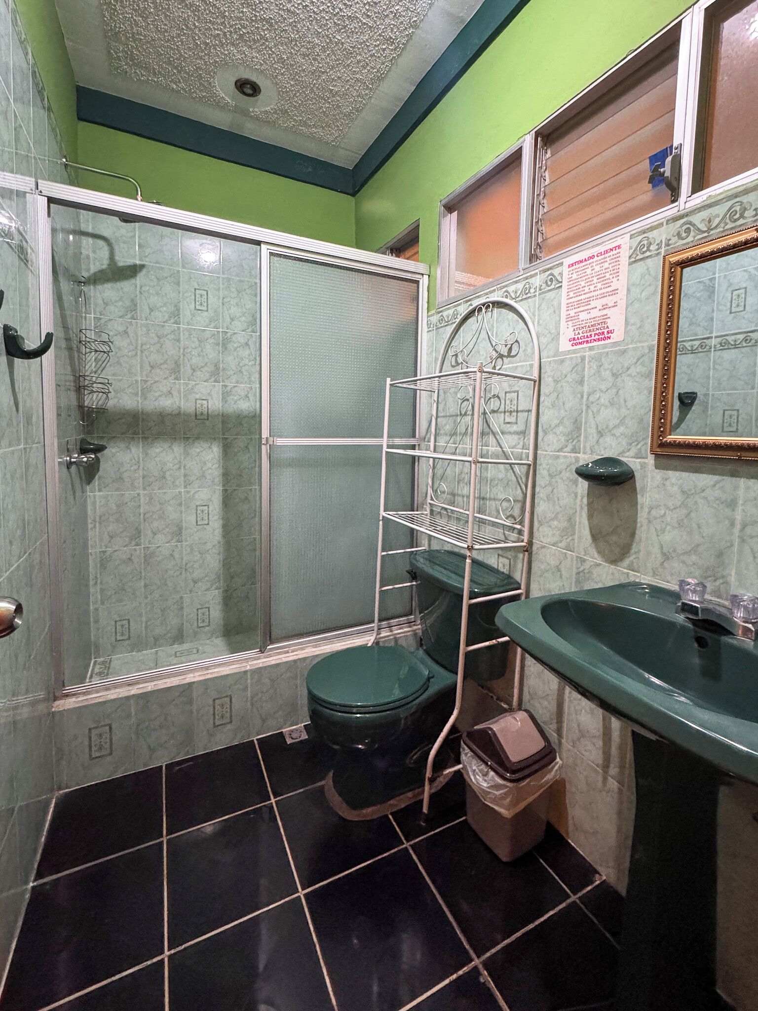 Un baño con ducha, inodoro, lavabo y un tendedero de metal.