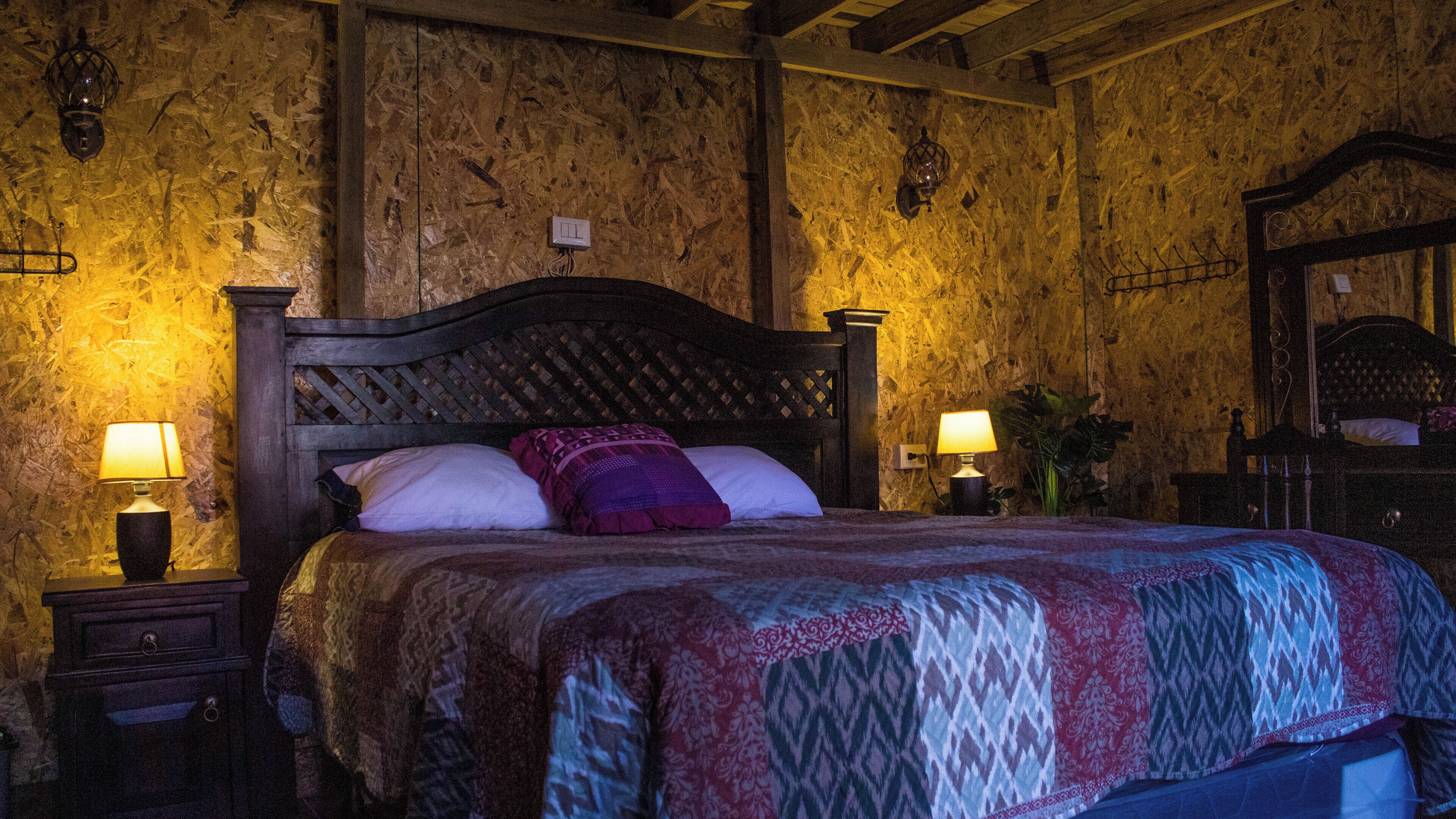 A bed with a wooden headboard, two bedside lamps, and a patterned bedspread.