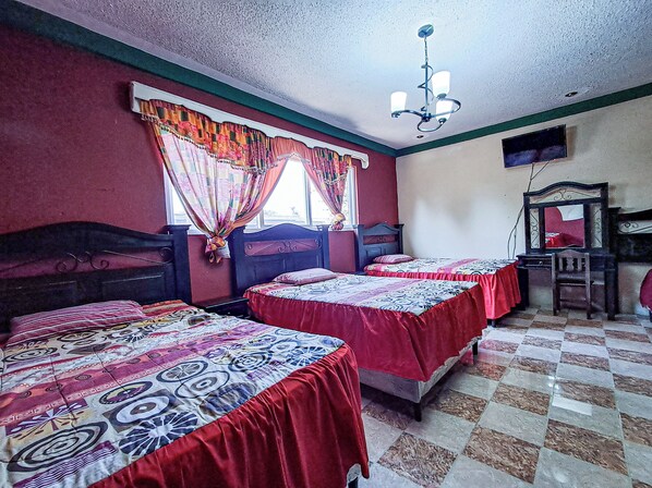 Une chambre avec deux lits, une chaise, une table, un miroir et un lustre.