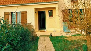 A two-story house with a tiled roof, a front entrance, and a small garden area. - Charming house 40 min from Paris (Bondoufle)