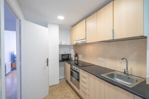A compact kitchen with a stainless steel sink, a microwave, and a stove. - HomeHolidaysRentals Magic - Costa Barcelona (Pineda de Mar)