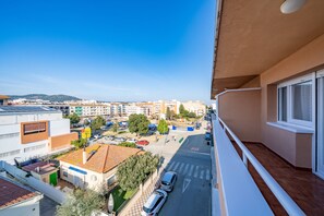 A balcony with a view of a city street, buildings, and a distant hill. - HomeHolidaysRentals Magic - Costa Barcelona (Pineda de Mar)