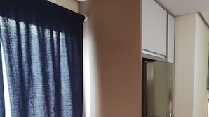 Una cocina con un refrigerador de acero inoxidable, un fregadero y una ventana con cortinas oscuras.