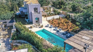 Eine moderne Villa mit Swimmingpool, Sitzgelegenheit im Freien und einem Garten.