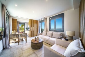 Ein modernes Wohnzimmer mit einer Couch, einem Esstisch mit Stühlen, einem Couchtisch und Blick ins Freie.
