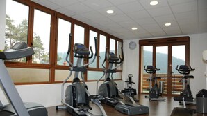 Une salle de sport équipée de tapis de course, de vélos elliptiques et d’un banc de musculation.