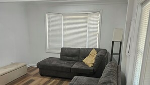 A living room with a sectional sofa, a bench, and a floor lamp. - Close 2 Masters Newly Renovated  3-bedroom 2.5 bath home in lovely North Augusta (North Augusta)