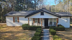 A single-story white house with a front porch, a small attached garage, and a pathway leading to the entrance. - Close 2 Masters Newly Renovated  3-bedroom 2.5 bath home in lovely North Augusta (North Augusta)