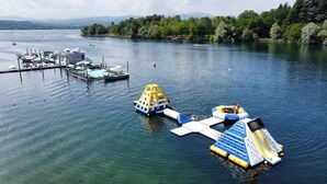 A lake with boats, a dock, and inflatable water structures. - Camping Italia Lido Mobilehome Happy Comfort for 5 people (Castelletto Sopra Ticino)