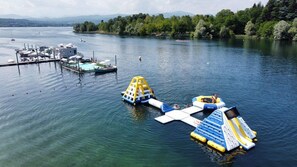 Ein See mit Booten, einem Steg und schwimmenden Wasserspielen.