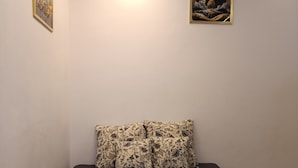 A bedroom with a bed, a nightstand, a wall-mounted light, and two framed pictures.