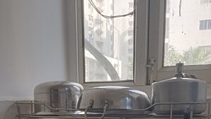 A kitchen with a dish rack holding various kitchenware, a window with a view of buildings, and a black countertop.