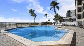 Una piscina amb un indicador de profunditat de 3 peus, envoltada de gandules i palmeres, i un edifici al fons.