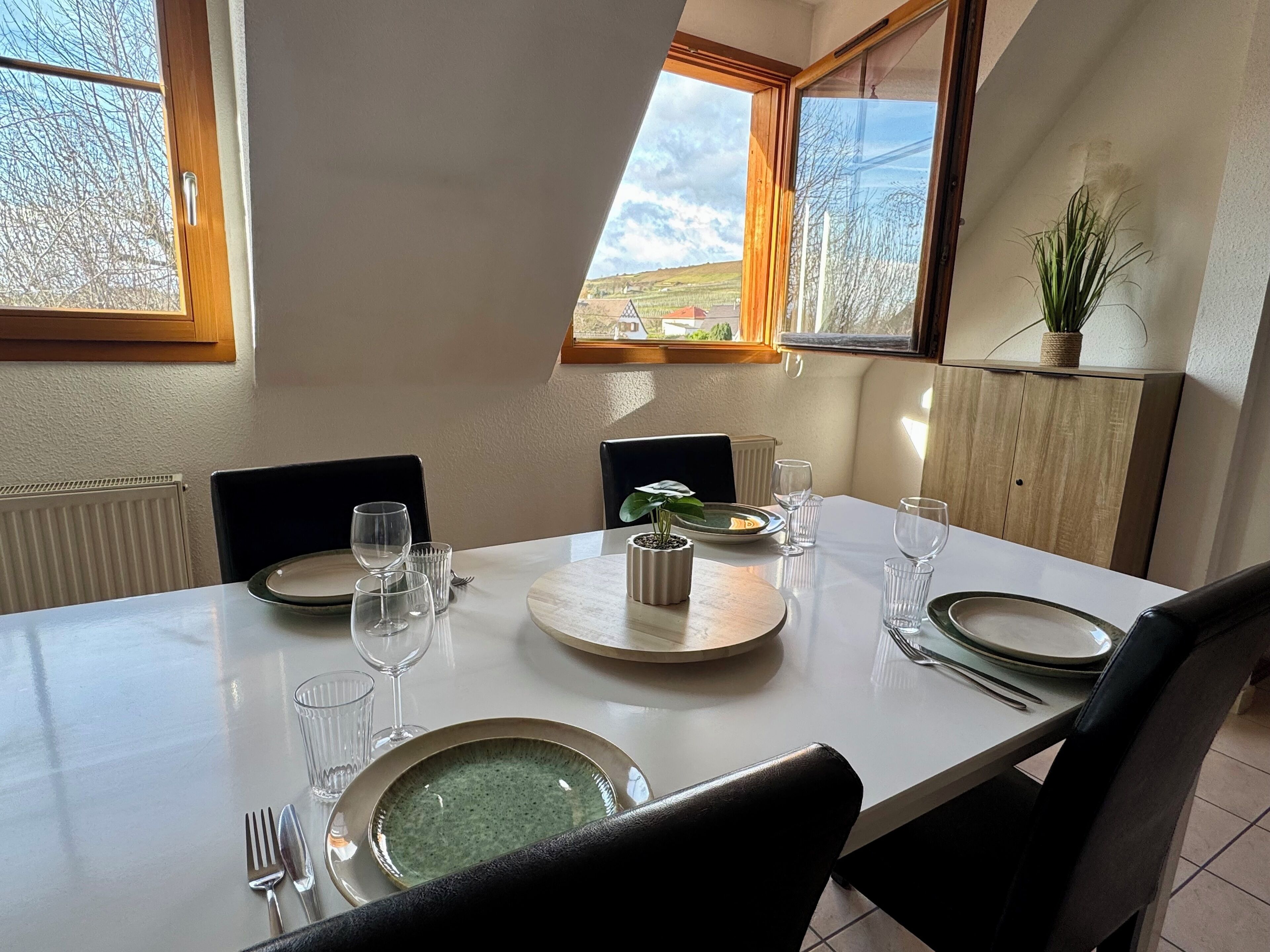 Een eettafel voor vier personen met uitzicht op het landschap door grote ramen.