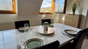 A dining table set for four with a view of the countryside through large windows. - Spacious, quiet apartment in the heart of Rouffach (Rouffach)