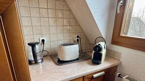 A kitchen with a toaster, kettle, and a window with a view of trees. - Spacious, quiet apartment in the heart of Rouffach (Rouffach)