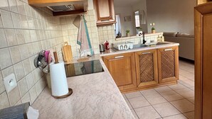 A modern kitchen with a marble countertop, wooden cabinets, and a built-in sink. - Spacious, quiet apartment in the heart of Rouffach (Rouffach)