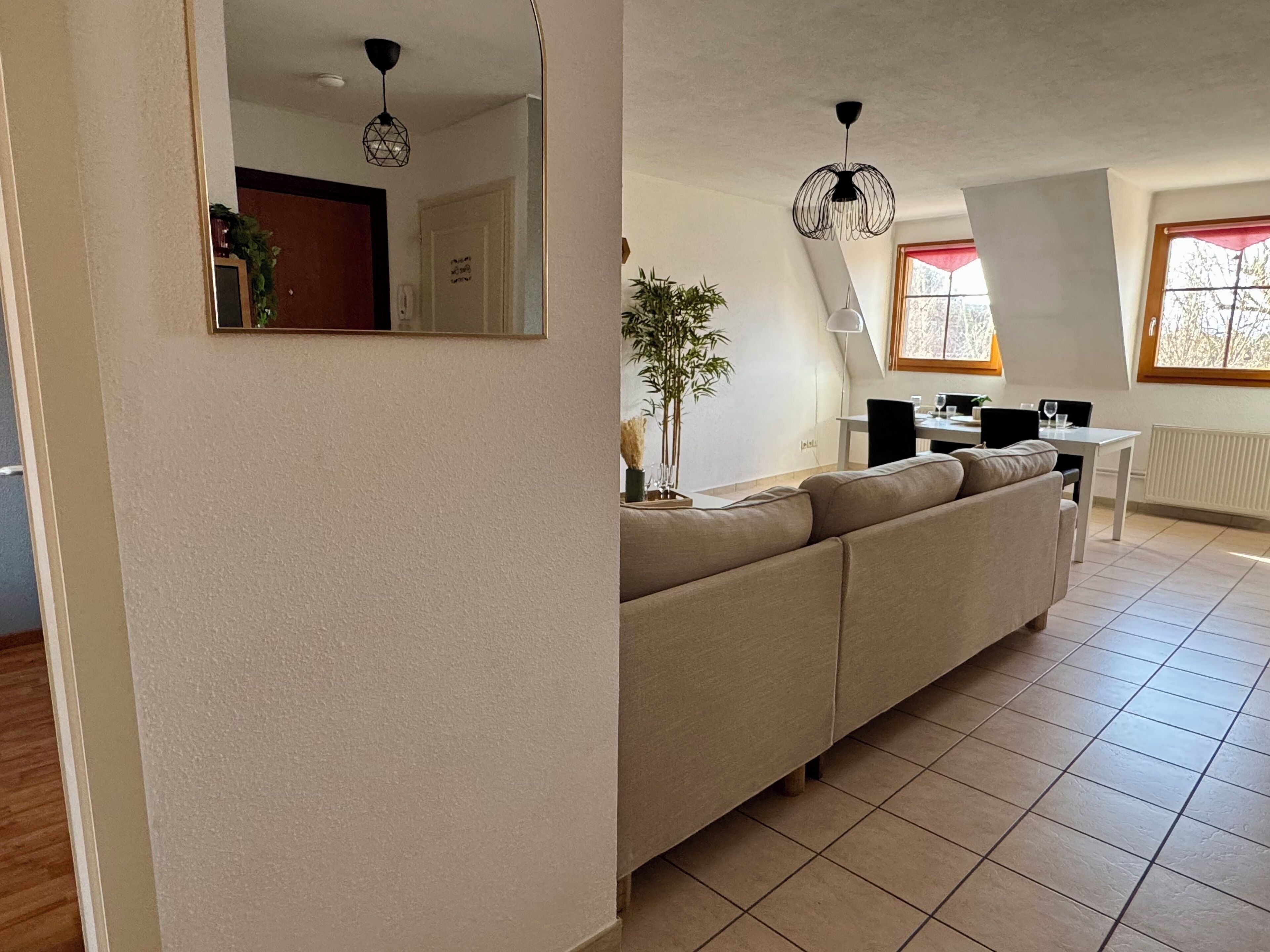 Una sala de estar moderna con un sofá, una mesa de comedor y un espejo grande.