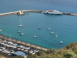 A marina with multiple sailboats docked, a large ferry, and a lighthouse. - Casa Pico Castelo – Tranquil Retreat on the Charming Island of Porto Santo (Porto Santo)