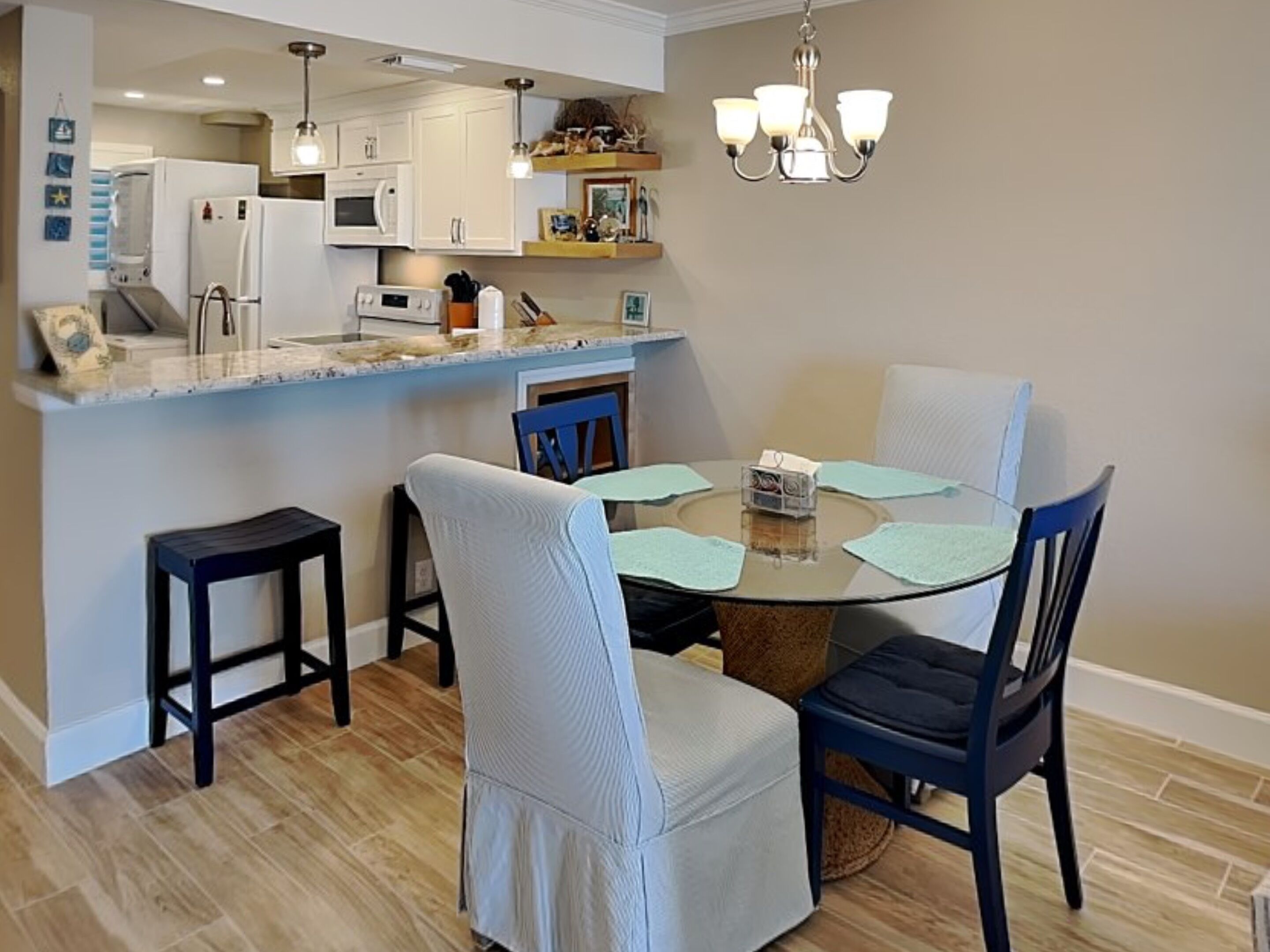 A modern kitchen with white cabinets, a built-in microwave, and a hanging light fixture.