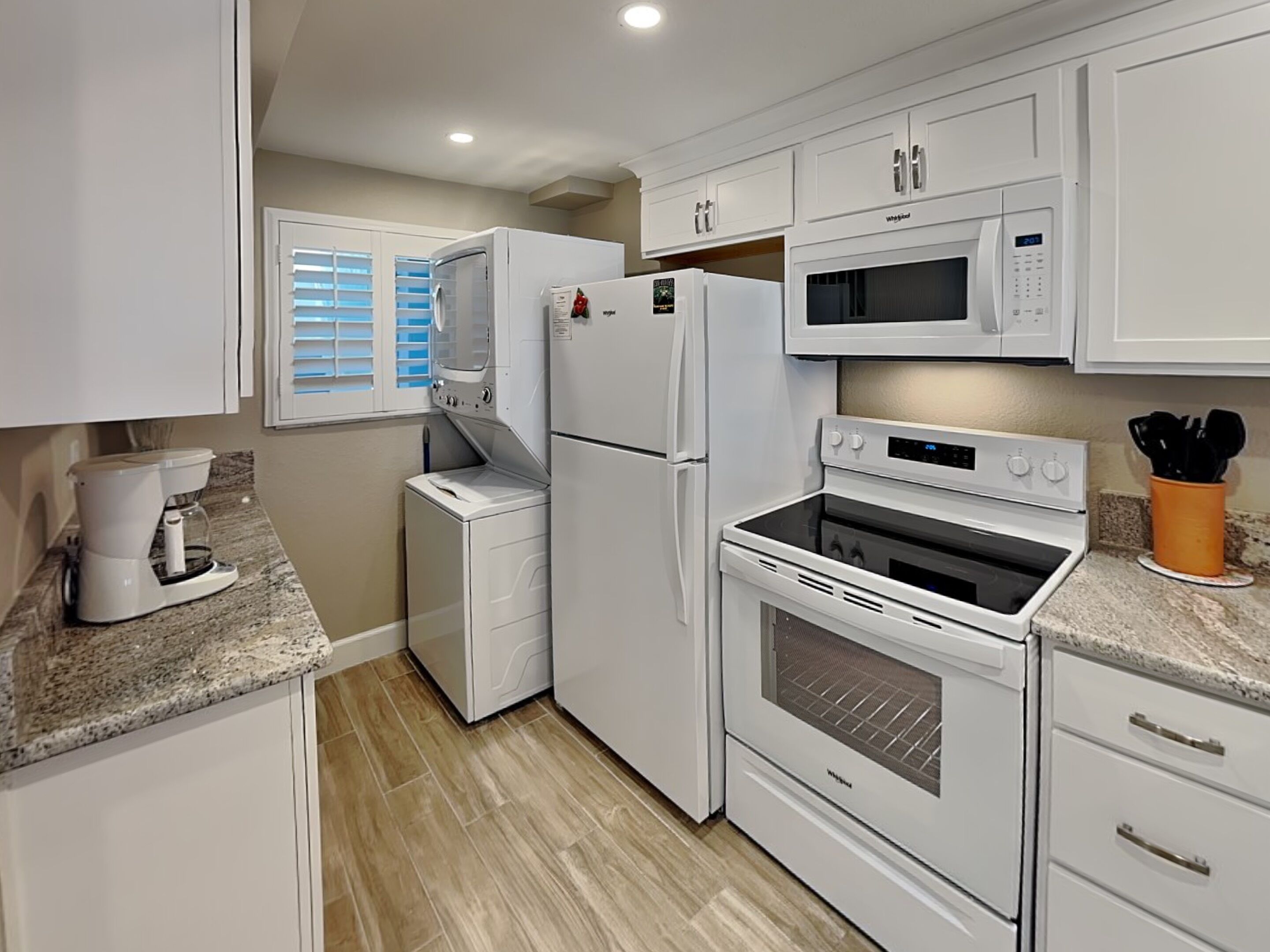 A compact kitchen with white appliances, including a refrigerator, microwave, and oven.