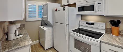 A compact kitchen with white appliances, including a refrigerator, microwave, and oven.