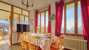 A dining area with a table set for four, a television, and a view of the outdoors. - CASA PATRON-Large Italian Alps Holiday Home Italy- 1h from Turin- Pet friendly (Pecco)