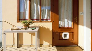 A wooden door with a window and a small table with books and a potted plant. - CASA PATRON-Large Italian Alps Holiday Home Italy- 1h from Turin- Pet friendly (Pecco)