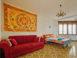 A room with a red sofa, a colorful bed, a large tapestry, and a chandelier. - CASA PATRON-Large Italian Alps Holiday Home Italy- 1h from Turin- Pet friendly (Pecco)